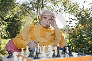 Senior man lying on chess board in a garden in the style of emotionally charged portraits