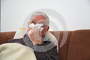 A senior man lying and sniffling in handkerchief photo