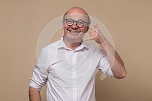 Senior man making call gesture asking to phone him as soon as possible.