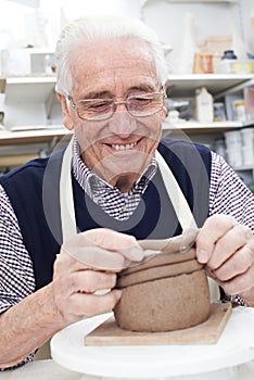 Senior Man Making Coil Pot In Pottery Studio