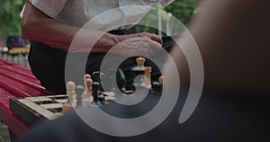 Senior man making a move during a chess game with his friend outdoors