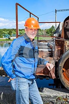 Senior man mechanist stands near sewage treatment plant