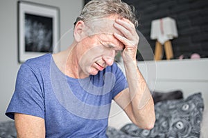 Senior man with migraine holding hand on forehead