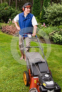 Senior man mowing lawn.