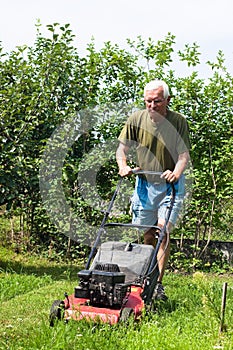 Senior man mowing lawn