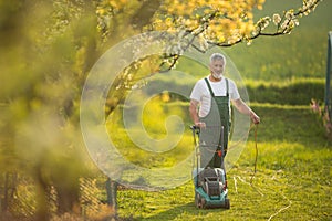 Senior man mowing the lawn in his garden