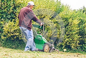 Senior man mowing the lawn with lawnmower