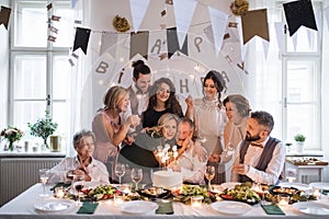 A senior man with multigeneration family celebrating birthday on indoor party.