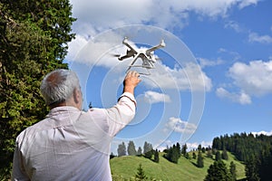 Senior man navigates unmanned aerial vehicle among nature