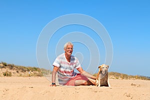 Senior man with old dog at beach