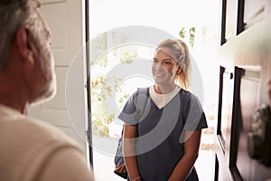 Senior man opening his front door to a female healthcare worker making a home health visit