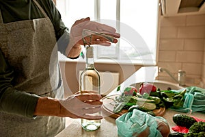 Senior man opening wine bottle with corkscrew