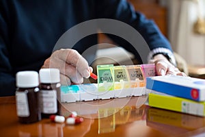 Close Up Of Senior Man Organizing Medication Into Pill Dispenser photo