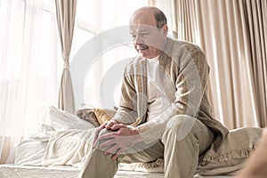 Senior man with osteoarthritis pain holding hands on his knee