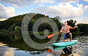 Senior man paddleboarding on lake in summer. Copy space. photo