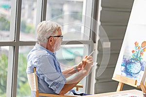 Senior man painting on canvas at home, Elderly man painting on a canvas, Happy retirement concepts