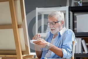 Senior man painting on canvas at home, Elderly man painting on a canvas, Happy retirement concepts