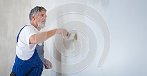 Senior man painting a room of rental appartment