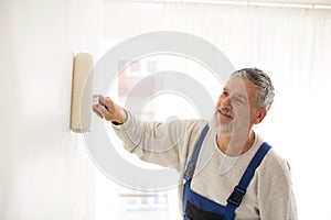 Senior man painting a wall in his home