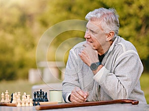 Senior man, park and thinking for chess, game and competition at table by trees, sunshine and focus. Elderly board game