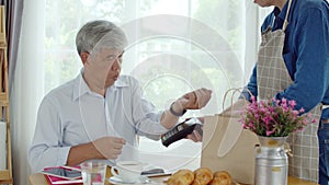 Senior man paying order with smart watch in coffee shop