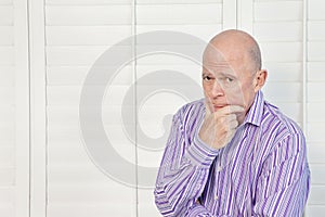 Senior man in pensive mood with hand on chin