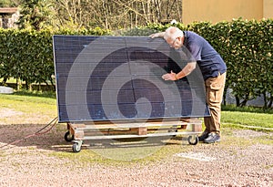 Senior man with photovoltaic solar panel in the garden