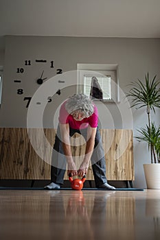 Senior man in pink shirt working out and exercising with a kettlebell