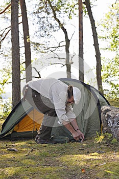 Senior man pitches a tent