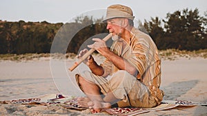 Senior man playing bamboo flute on the beach