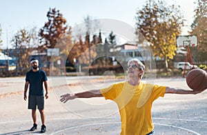 Senior man playing basketball with his son in a park