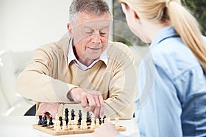 Senior Man Playing Chess With Teenage Granddaughter