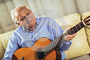 Senior man playing guitar at home