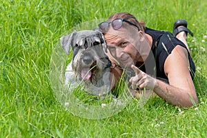 Senior man playing with his dog lying on the grass in the park.