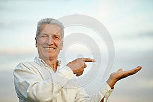 Senior man pointing on sky background