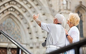 Senior man pointing to his wife at old cathedral