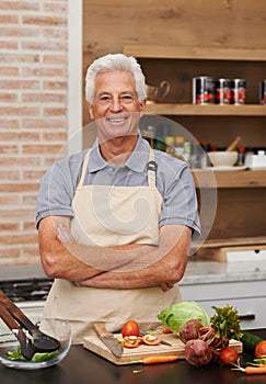 Senior man, portrait and arms crossed in cooking, food and vegetables with apron and smile in kitchen. Mature person