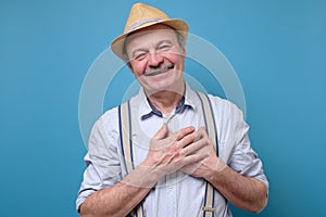 Senior man posing in studio smiling joyfully, being pleased with compliment