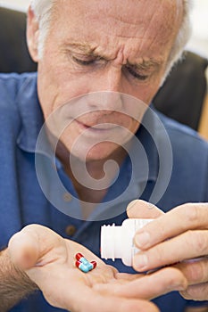 Senior Man Pouring Pills Out Of Bottle