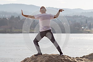 Senior man practicing tai chi chuan on beach