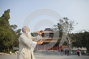 Senior Man Practicing Tai Ji in Front of Traditional Chinese Building