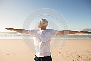 Senior man practicing yoga at beach