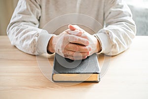 Senior man praying, reading  an old Bible in his hands