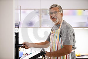 Senior man prepares healthy veggies in the oven, photo