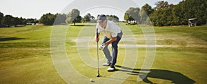 Senior man preparing to putt on a golf green