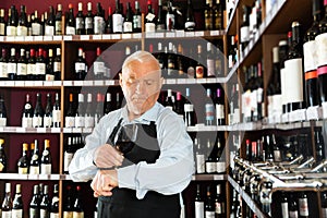 senior man professional sommelier tasting red wines in wine store