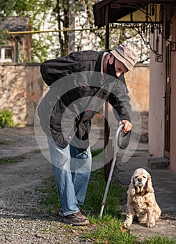 Senior man in protective mask with a cane walking with a dog