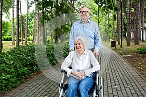 Senior man pushing senior woman in the wheel chair