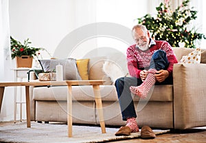 A senior man putting socks on at home at Christmas time.