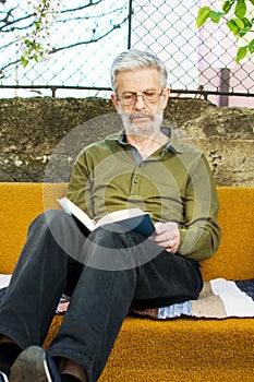 Senior man reading a book in the backyard